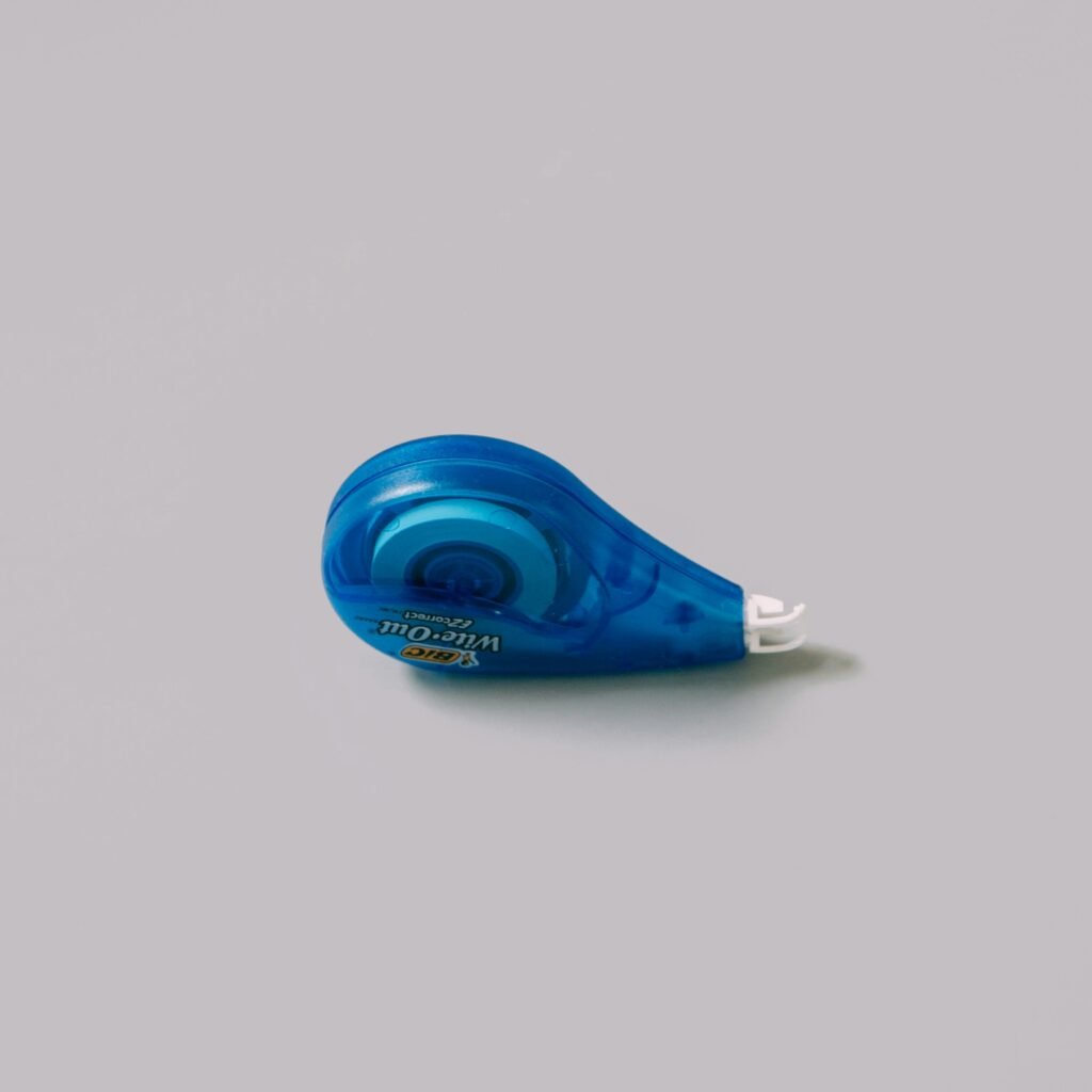 Image for Writing Compelling Copy: a white-out device sits on an off-white background. It has a blue case.