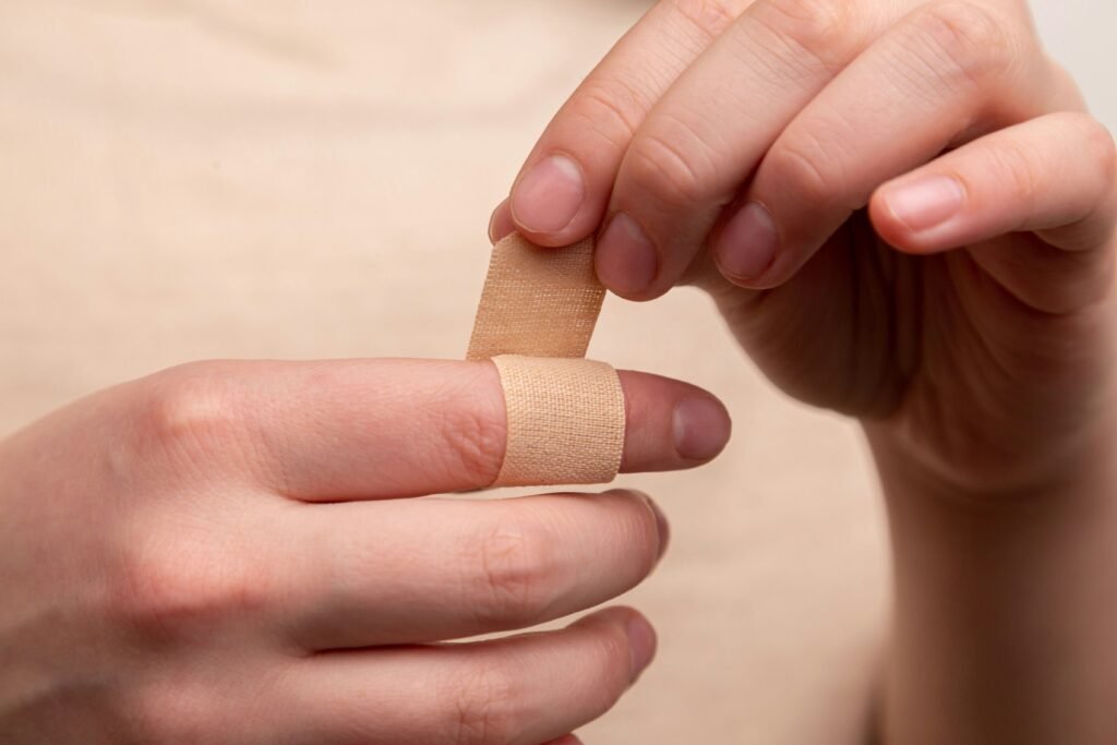 Image for Writing Compelling Copy: Two light skinned hands belonging to the same person apply a band-aid to a finger. The colours are largely neutral and cream coloured.