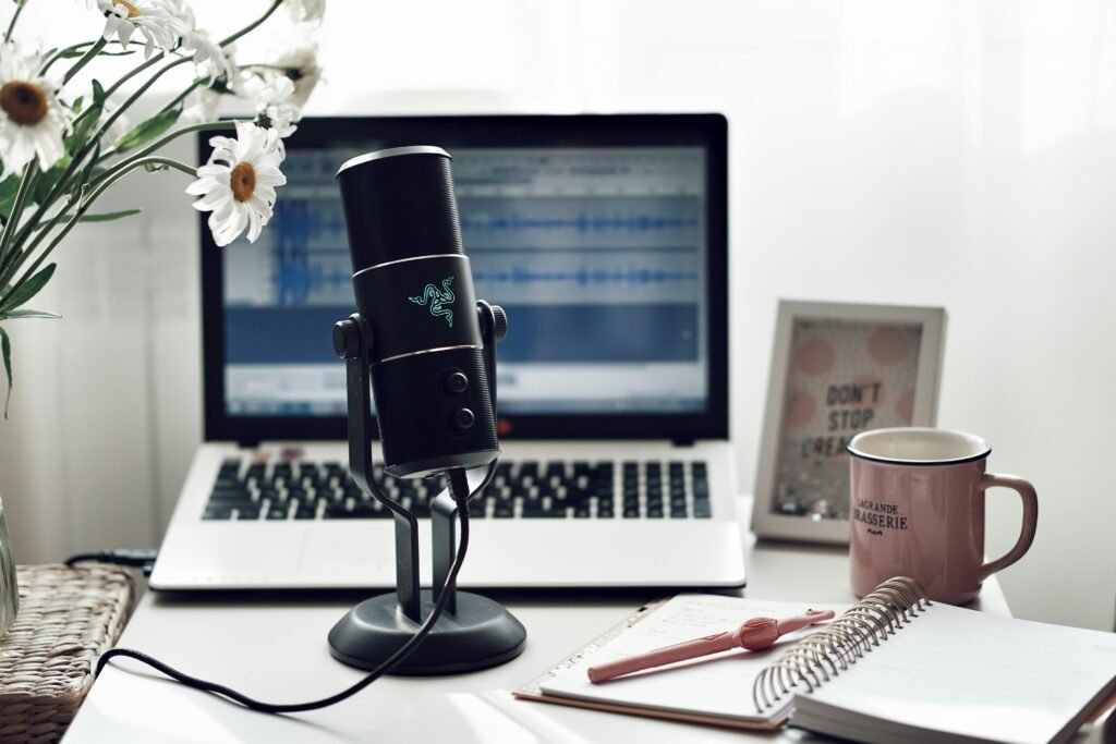 A microphone sits near a laptop with books and other supplies nearby. This is for an article about assertiveness in branding.