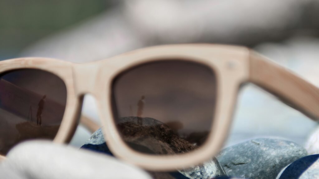 A pair of wooden framed sunglasses sit on a rocky beach. This is for an article about building a business.